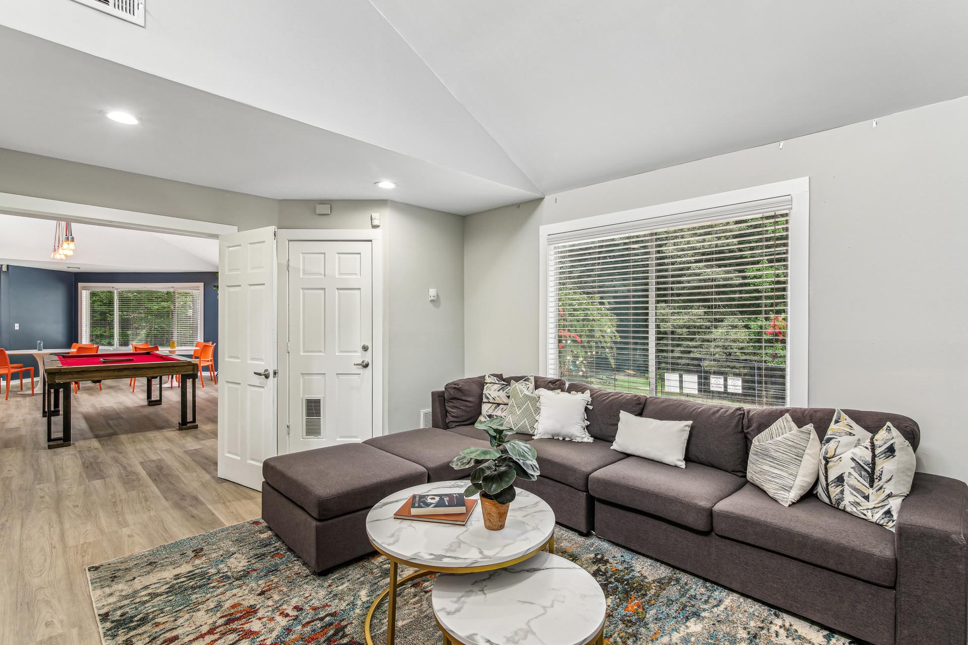 Clubroom with large sectional sofa and pool table in background.