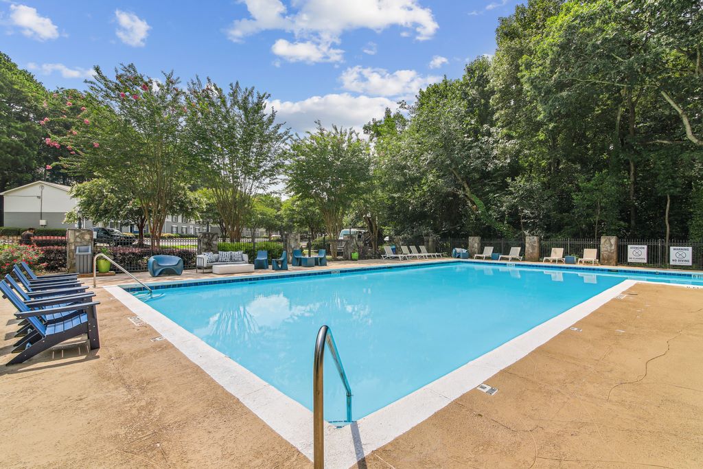 Swimming pool with sundeck and lounge chairs surrounded by native landscaping.